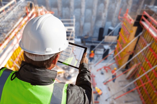 Um homem com um capacete em uma construção usando um tablet